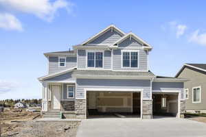 Craftsman-style house with driveway, a garage, a shingled roof, and stone siding
