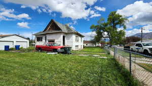 View of property exterior featuring a detached garage, fence, and a lawn