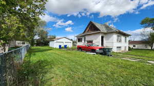 Rear view of house with a chimney, a yard, fence, an outbuilding, and a detached garage