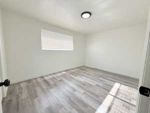 Unfurnished room with visible vents, light wood-type flooring, and baseboards
