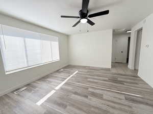 Spare room with light wood finished floors, ceiling fan, and baseboards