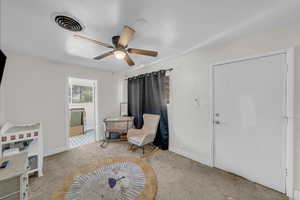Living area featuring carpet flooring, visible vents, ceiling fan, and baseboards