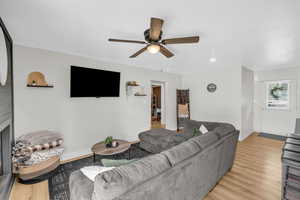 Living area featuring recessed lighting, light wood-style floors, ceiling fan, a fireplace, and baseboards