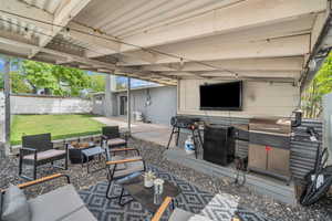 View of patio with fence and an outdoor living space with a fire pit