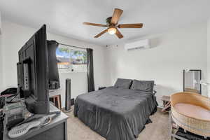 Bedroom with an AC wall unit, a ceiling fan, and light colored carpet