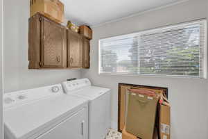 Laundry room with independent washer and dryer, crown molding, cabinet space, and baseboards