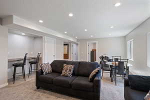 Living area featuring baseboards, recessed lighting, a textured ceiling, and light colored carpet