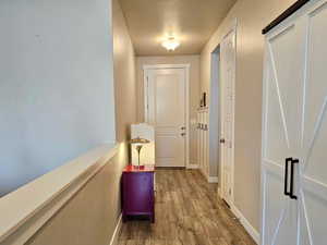 Corridor featuring a textured ceiling, baseboards, and wood finished floors