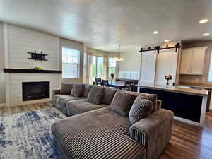 Living area featuring wood finished floors, a fireplace, recessed lighting, a barn door, and a textured ceiling