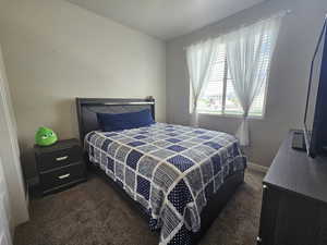 Bedroom with dark colored carpet and baseboards