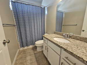 Bathroom featuring vanity, tile patterned flooring, a shower with curtain, and toilet