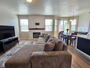 Living room featuring a wealth of natural light, a fireplace, a textured ceiling, and a notable chandelier