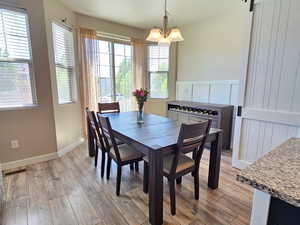 Dining space featuring light wood-style floors, baseboards, a healthy amount of sunlight, and an inviting chandelier