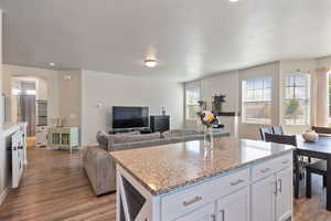 Kitchen featuring wood finished floors, a kitchen island, open floor plan, a textured ceiling, and white cabinets