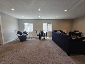 Carpeted living area with recessed lighting, a textured ceiling, and baseboards