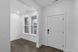 Foyer entrance featuring visible vents, dark wood-style flooring, and baseboards
