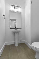 Half bath with toilet, tile patterned flooring, and baseboards