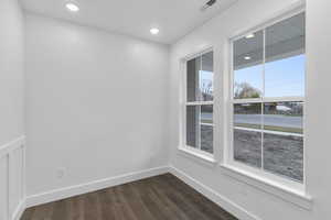 Spare room with baseboards, visible vents, dark wood-style flooring, and recessed lighting