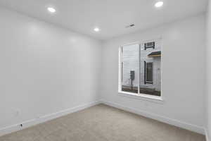 Carpeted spare room featuring recessed lighting, visible vents, and baseboards