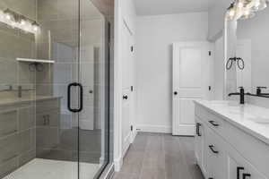 Bathroom featuring double vanity, a shower stall, baseboards, and a sink