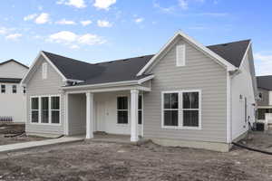 View of front facade with roof with shingles, central AC unit, and a porch
