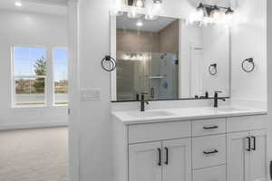 Full bath featuring a stall shower, double vanity, a sink, and baseboards