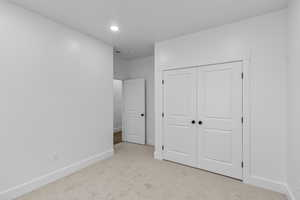 Unfurnished bedroom with recessed lighting, a closet, light colored carpet, and baseboards