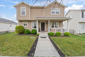 Traditional-style house featuring a porch, a front lawn, and central AC unit
