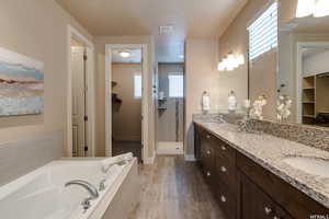 Bathroom featuring a shower stall, double vanity, visible vents, a garden tub, and a walk in closet