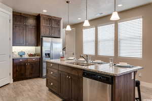 Kitchen with a sink, stainless steel appliances, light wood-style floors, visible vents, and hanging light fixtures
