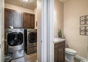 Laundry room featuring cabinet space, washing machine and dryer, light wood-type flooring, visible vents, and baseboards
