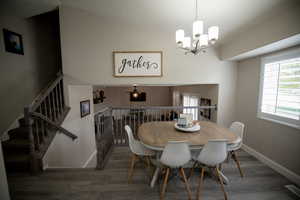 Dining room featuring baseboards, an inviting chandelier, wood finished floors, and lofted ceiling