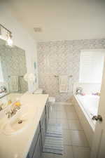 Bathroom with tile patterned flooring, a garden tub, visible vents, vanity, and toilet