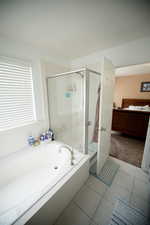 Full bath with tile patterned flooring, a bath, and a stall shower
