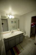Bathroom with vanity, tile patterned flooring, toilet, and a textured ceiling