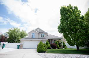 Traditional-style house with fence, an attached garage, concrete driveway, and a front yard