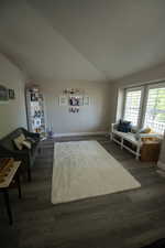 Living room with baseboards, vaulted ceiling, and dark wood finished floors
