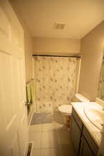 Full bathroom featuring toilet, tile patterned floors, visible vents, and vanity