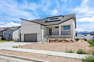 View of front of house featuring a porch, driveway, stone siding, roof mounted solar panels, and roof with shingles