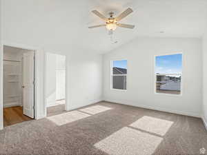 Unfurnished bedroom with baseboards, carpet floors, a walk in closet, visible vents, and lofted ceiling
