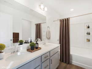 Full bath with visible vents, shower / bath combination with curtain, double vanity, and a sink