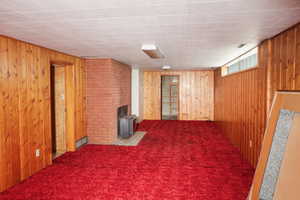 Basement featuring wood walls, a wood stove, and carpet flooring