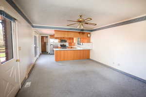 Kitchen with brown cabinets, stainless steel appliances, a peninsula, baseboards, and baseboard heating