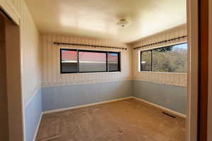 Carpeted spare room with visible vents, wallpapered walls, and baseboards