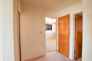 Hallway featuring light carpet