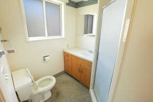 Bathroom with baseboards, a stall shower, toilet, and vanity