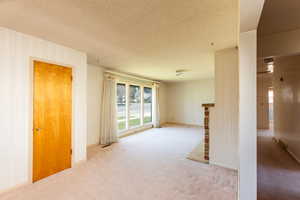 Empty room with a wealth of natural light, carpet floors, and a textured ceiling