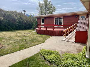 Exterior space featuring a deck, a yard, and brick siding