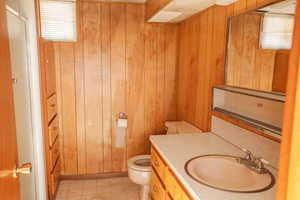 Bathroom with wood walls, an enclosed shower, toilet, and vanity