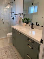 Bathroom featuring vanity, toilet, and a marble finish shower